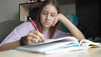 girl is doing homework. A girl in a blouse gets bored while doing homework. A female student is tired in class. A schoolgirl