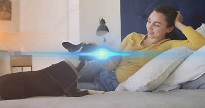Pregnant woman reclining on bed teasing dog with treat then petting for gentle health bonding