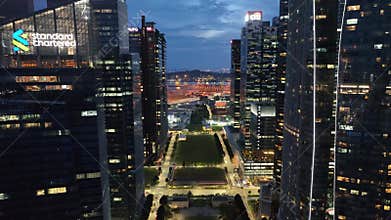 Real-time aerial video of sunset in Singapore skyline. Flight over the wall of skyscrapers in night lights