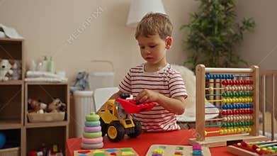 Boy playing with toy truck and learning abacus in cozy indoor kindergarten setting