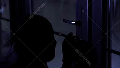 male thief in balaclava and gloves using master key to pick door lock to enter apartment at night, close up