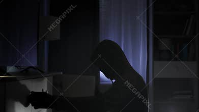 robbery, a thief in black clothes and a balaclava rummages through other people's things in search of valuables at