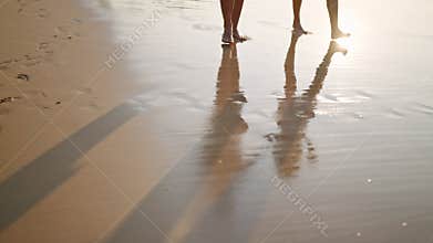 Man, woman feet walk barefoot in sea surf water edge. Reflection of couple with coconut cocktails on wet beach sand