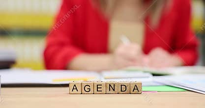 Word Agenda from cubes against businesswoman making notes