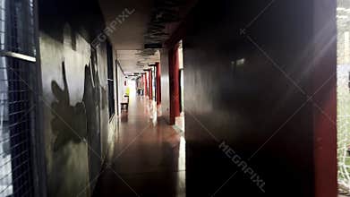Long corridor with light illuminating the building interior. Dark inside walls reflect empty halls
