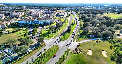 Cars on street and the buildings of Champions Gate neighborhood surrounded by greenery in Florida