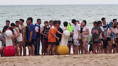 Nha Trang, Vietnam - 02 January, 2025: Asians stand on the beach, inflatable unicorns beside them, waiting for the team