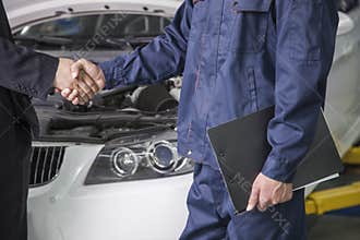 Businessman shaking hands with Mechanic in Auto Repair Shop