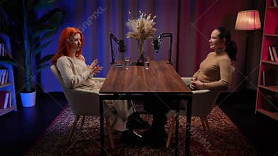 Two Influencers of women being interviewed in a loft-style podcast studio