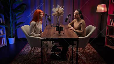 Two Influencers of women being interviewed in a loft-style podcast studio