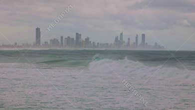 A personal water craft ride storm generated swells against a cityscape background.