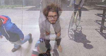 Crouching on sidewalk, man with glasses near bicycle and cyclist passing
