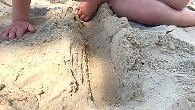 Child digs a hole in the sand on the beach