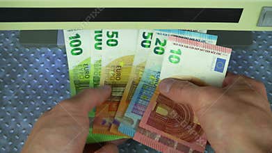 Man check bills on bill detector with UV light. Man hands took euros into bill detector. Checking euro banknotes in a UV light