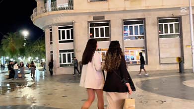 Evening stroll in a vibrant plaza with palm trees and families enjoying leisure time