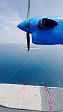 view from the water airplane window to the rotating propellers of the engine of a local airlines plane flying over the