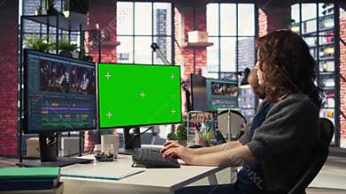 Female videographer making a movie montage next to green screen display