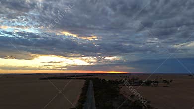 Drone Hyperlapse of a highway in expansive rural fields under dramatic sunset sky with dark clouds