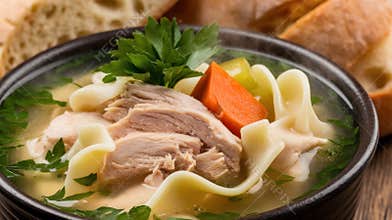 Delicious chicken noodle soup garnished with parsley, featuring tender chicken and fresh vegetables.