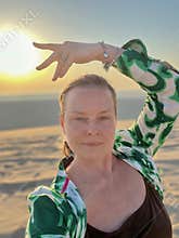 A 50-year-old woman poses in an emerald print tunic in the desert in Doha