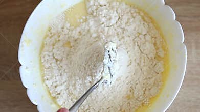 Flour being added to dough with spoon. Close-up shot, soft powder falling onto sticky mixture.