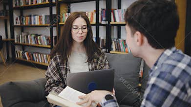 Engaging discussion between two students at a cozy library setting during a study session in the afternoon