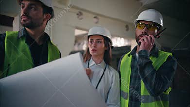 Three professional Caucasian builders colleagues discussing blueprint building in construction controller foremen