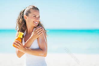 Young woman on beach applying sun block creme