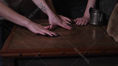 Close-up of young people spinning discs on a wooden board in a dark quest room.