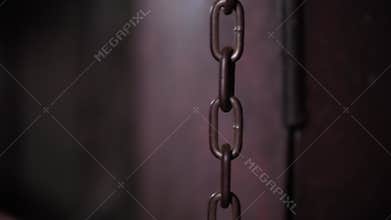 The chains are hanging on a gray wall with numbers and dashes in the quest room.