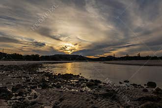 A sunset trying to happen through thick cloud over an estuary.