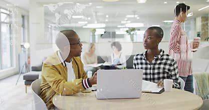 Man opening laptop starting tech data analysis while peer flipping notebook with animated charts