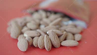 Almonds are spilled from a bag onto a bright surface,