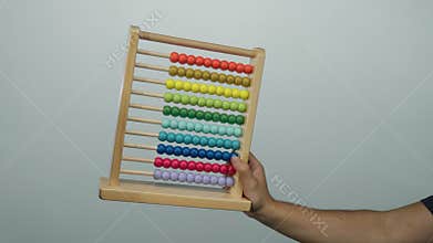 Man holding colorful abacus against white isolated wall background, showcasing educational and mathematical wooden tool with
