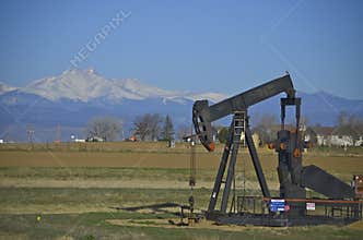 Oil well, pump jack with snow capped mountains