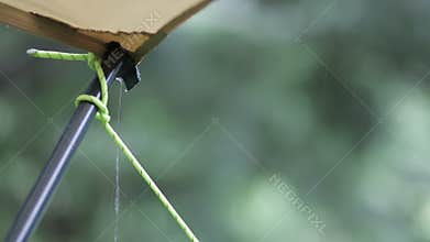 Raindrops falling from awning tarp tent at campsite.
