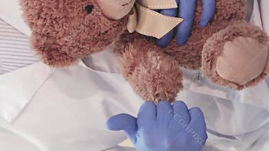 Caring doctor holds a teddy bear and gives a thumbs-up