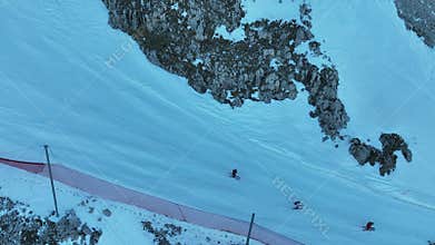 Group of people skiing in the mountains on a sunny winter day. Ski lessons with local instructors. Children learn to ski with an