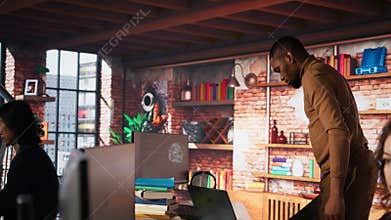 Man entering startup agency office holding laptop