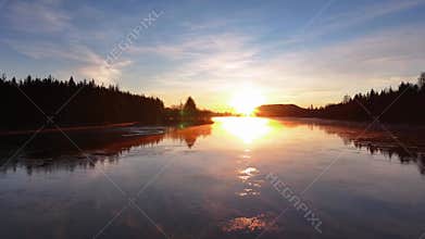 Drone footage of the mist floating over a frozen lake at sunset
