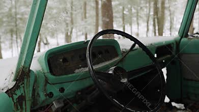 Closeup revealing shot of the inside of an abandon classic truck in a winter forest covered in snow