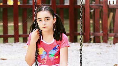 Sad young girl sits on swing