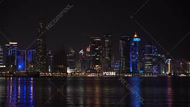Doha, Qatar - Colorful illuminated skyline of Doha at night with traditional wooden boats called Dhows in the foreground