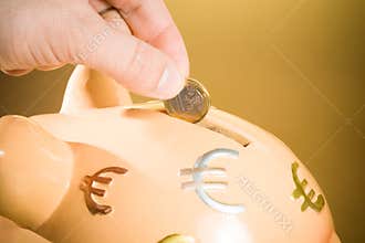 Hand inserting a coin into a piggy bank, concept for business and save money