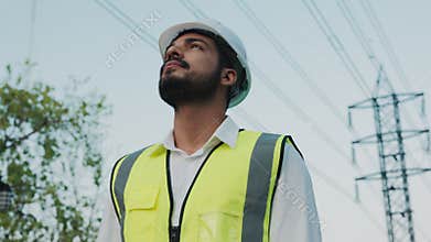 Portrait of engineer in safety vest looking around at buildings and utilities