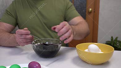 4k. A male person takes Easter eggs out of violets of dye and puts them on a