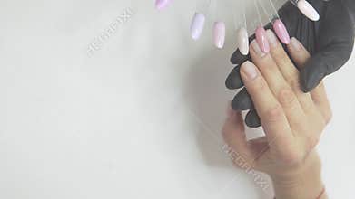 A woman presents vibrant nail polishes and designs, showcasing creativity