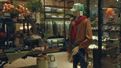 Mannequin displayed in decorative clothing shop with blurred background showcasing apparel and a variety of accessories, creating