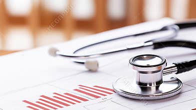 Medical stethoscope lying near health progress chart with rising data bar graph representing positive patient outcomes