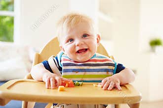 Baby Boy Eating Fruit In High Chair